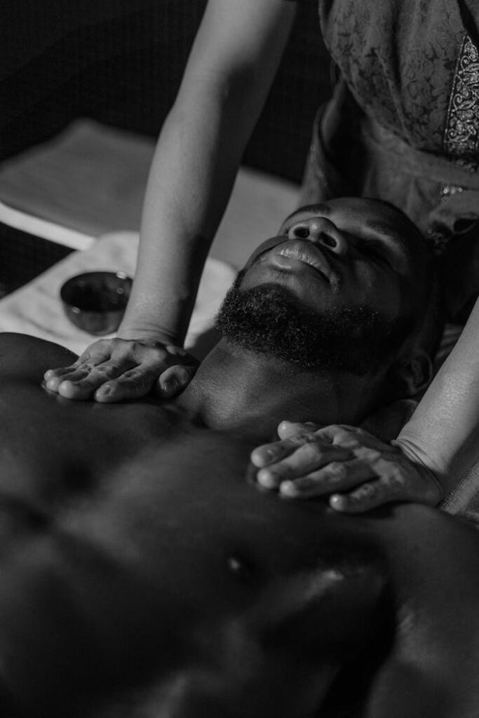 A professional male therapist demonstrating Swedish Flow techniques with smooth, flowing movements designed to relax the body and ease muscle tension. Black and white photo of a man receiving a relaxing massage promoting self-care and wellness.